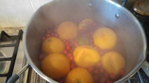 Oranges and cranberries boiling in a pan.
