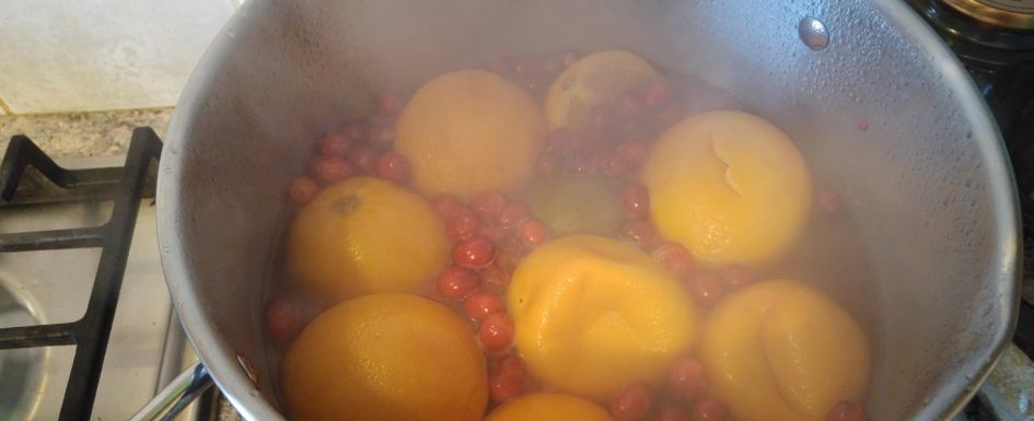 Oranges and cranberries boiling in a pan.